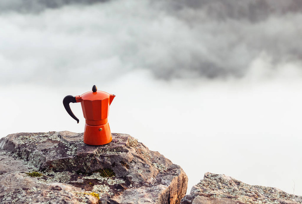 Cafetera con café caliente de pie en un acantilado rocoso al aire libre. Senderismo y camping utensilios de cocina y concepto de engranajes
 - Foto, Imagen
