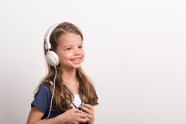 Portrait of a small girl with headphones in a studio. Copy space. - Fotó, kép