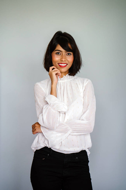 Portrait of a young, tall and slim Malay woman in a white shirt and black pants against a white background - Фото, зображення