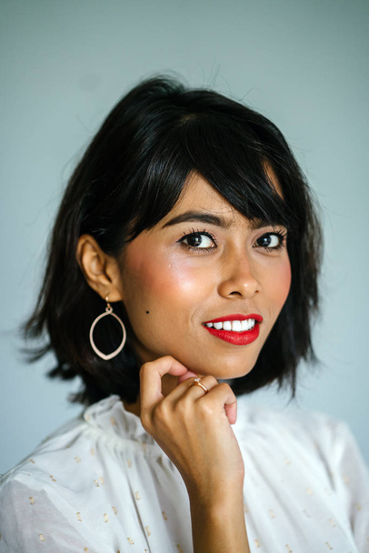 Portrait of a young, tall and slim Malay woman in a white shirt and black pants against a white background - Fotoğraf, Görsel