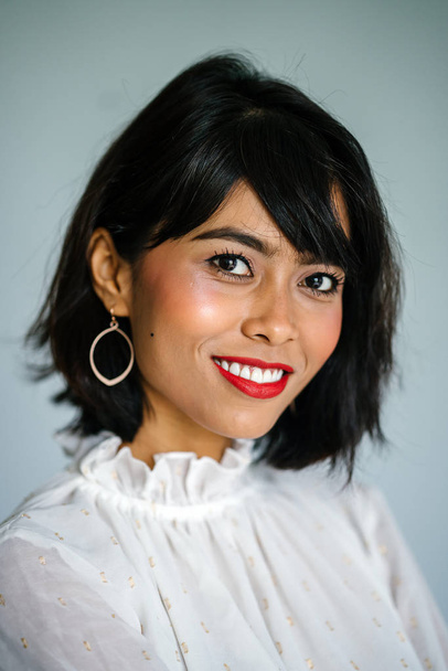 Portrait of a young, tall and slim Malay woman in a white shirt and black pants against a white background - Foto, Imagem