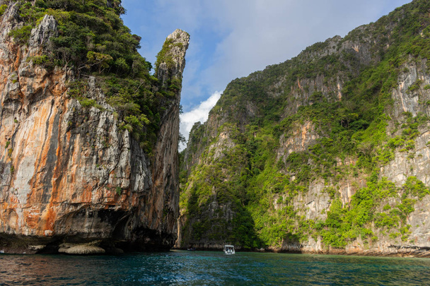 Koh Phi Phi, Thailand - May 9, 2018: Boat entering in a small bay in Koh Phi Phi Leh surrounded by high karst hills covered by green vegetation - Photo, image