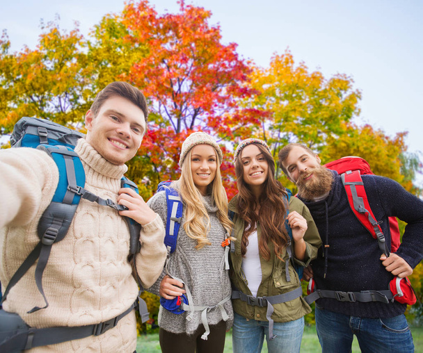 friends with backpacks taking selfie in autumn - Фото, изображение