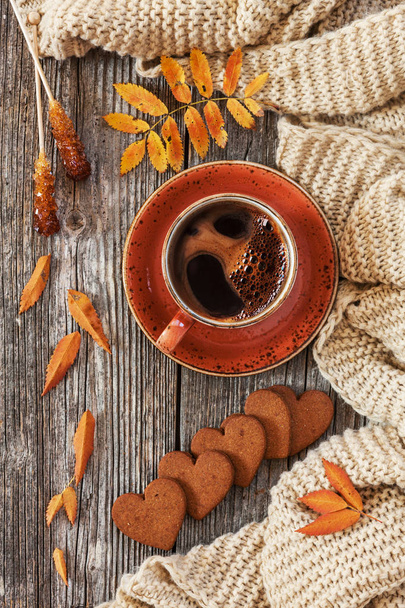 Cup of hot black coffee and heart-shaped gingerbread with autumnal leaves and warm scarf  on wooden vintage table, top view - Foto, Imagen