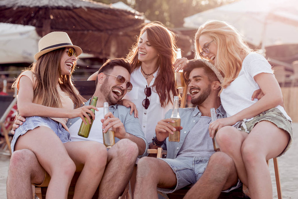 Ystävät juovat olutta ja pitävät hauskaa rantabileissä.Kesä, loma, loma, onnellisuus ja ihmisten käsite
. - Valokuva, kuva