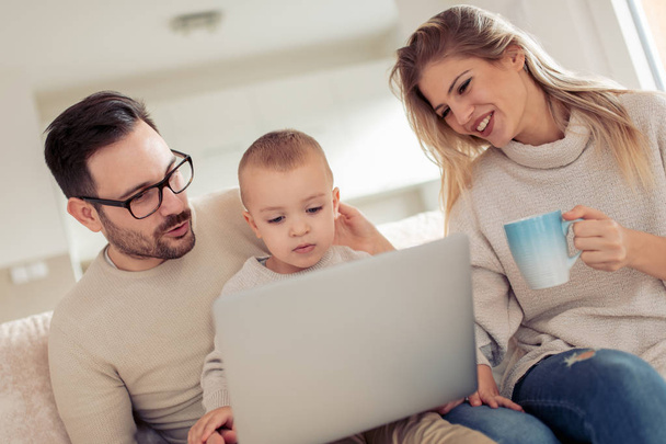 Les parents souriants et leur petit fils utilisant un ordinateur portable ensemble
. - Photo, image