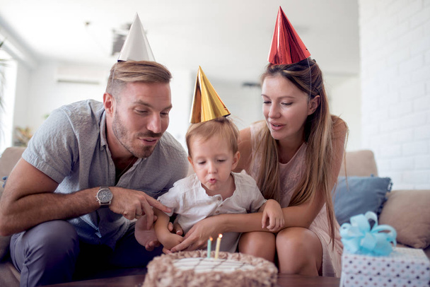 Happy family celebrating a birthday together at home in the living room. - Photo, Image