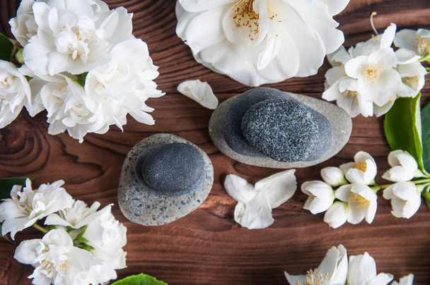 Pyramids of gray zen stones with beautiful fresh white flowers green leaves on wooden background. Concept of harmony, balance and meditation, spa, massage, relax - Fotoğraf, Görsel