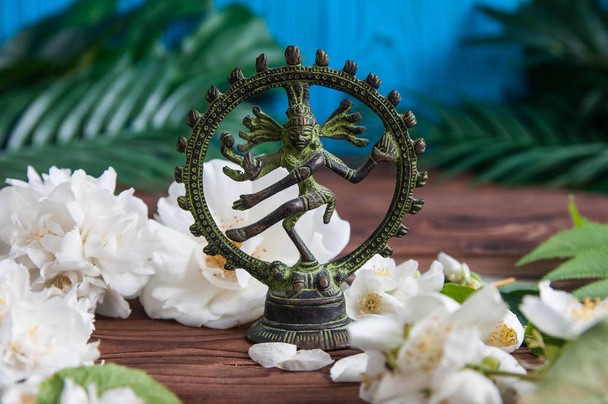 美しい新鮮な白い花の緑の葉と木製の背景にインドの神シヴァNataradja像と灰色の禅の石のピラミッド。調和、バランスと瞑想、スパ、マッサージ、リラックスの概念 - 写真・画像