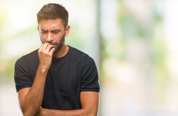 Volwassen Spaanse man over geïsoleerde achtergrond op zoek gestresst en nerveus met handen op mond nagels te bijten. Angst probleem. - Foto, afbeelding
