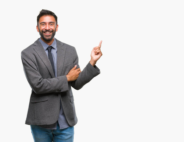 Homme d'affaires hispanique adulte sur fond isolé avec un grand sourire sur le visage, pointant avec la main et le doigt vers le côté regardant la caméra
. - Photo, image