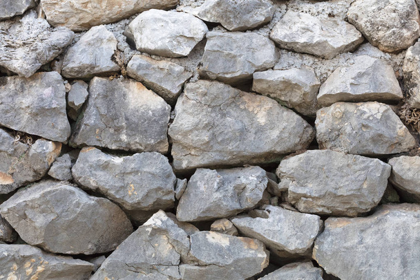 Het patroon van een oude stenen muur. Stenen uit een zandsteen, als achtergrond van een stenen muur. Abstracte achtergrond van oude stenen geplaveide close-up. - Foto, afbeelding