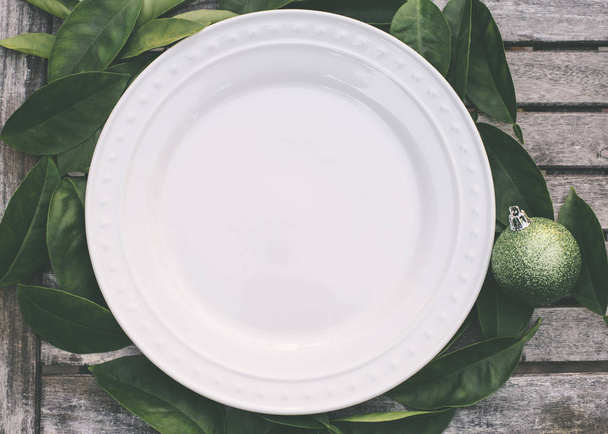 Regolazione rustica di Natale con piatto bianco e ornamento verde
 - Foto, immagini