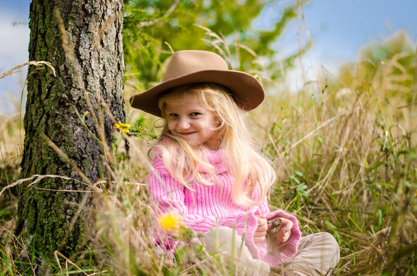 маленькая милая девочка с длинными светлыми волосами расслабляется в осеннем лесу
 - Фото, изображение