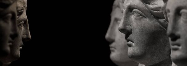 Мраморные древние головы женщин, смотрящих друг на друга на изолированном черном фоне
 - Фото, изображение