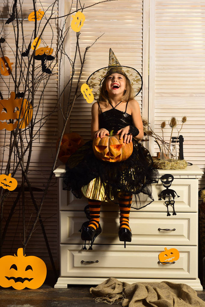 Kid in witch hat and costume holds jack o lantern - Foto, imagen