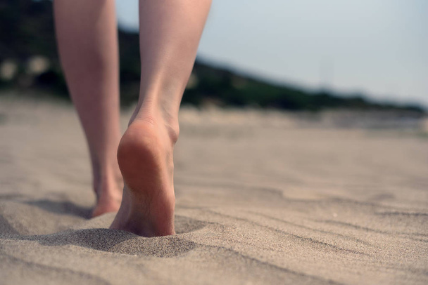 nackte Füße von Frauen, die auf dem Sand am Strand am Meer spazieren. - Foto, Bild
