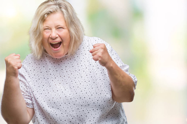 Senior plus koko valkoihoinen nainen yli eristetty tausta erittäin onnellinen ja innoissaan tekee voittaja ele kädet ylhäällä, hymyillen ja huutaen menestystä. Juhlan käsite
. - Valokuva, kuva