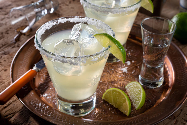 köstliche Tequila und Limetten-Margaritas auf einem Kupfer-Ladegerät mit grobem Salzrand. - Foto, Bild
