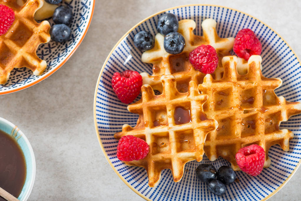 Traditional homemade belgian waffles with fresh berries and syrup on light background.  Cosy family breakfast concept.  Flat lay, top view. - Photo, Image