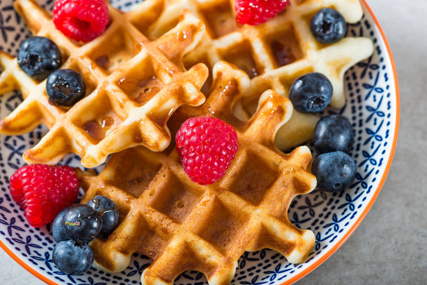 Traditional homemade belgian waffles with fresh berries and syrup on light background.  Cosy family breakfast concept.  Flat lay, top view. - Photo, Image