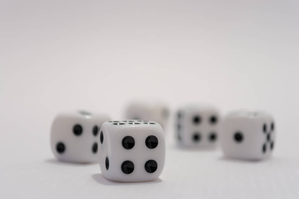 A close up of five white dice focused on the number four side of one dice. Numbers two, one, five and six are also visible in the image - Photo, Image