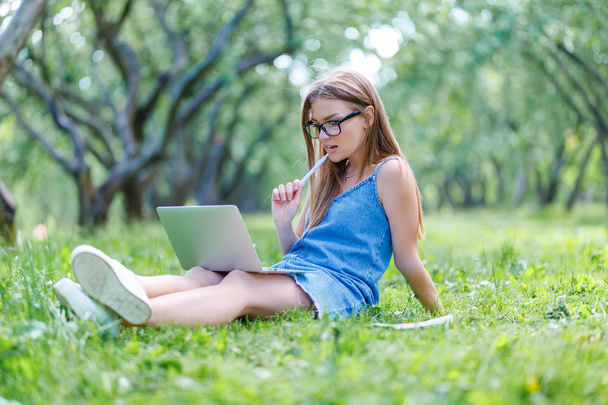 Student with notebook in park looking at computer - Foto, imagen