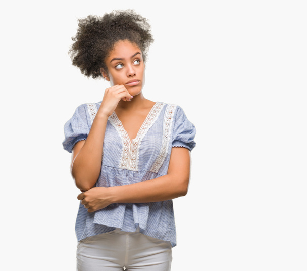 Young afro american woman over isolated background with hand on chin thinking about question, pensive expression. Smiling with thoughtful face. Doubt concept. - Фото, изображение