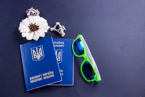 Dois passaportes ucranianos no exterior em um fundo preto com óculos e uma flor
 - Foto, Imagem
