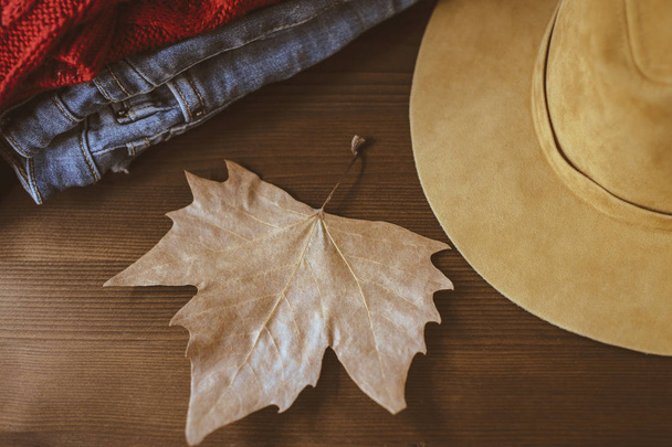 cozy autumn concept, warm autumn clothes and leaf over wooden nackground. Fall concept with warm colors  - Photo, Image