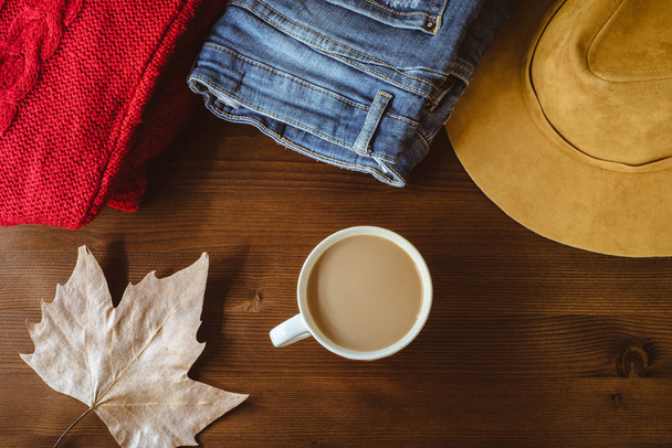 flat lay of autumn fall warm clothes cup of coffee and autumn leaf over wooden background. Autumn fall cozy concept - Photo, Image