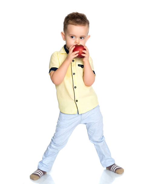 El niñito muerde una manzana.
. - Foto, imagen