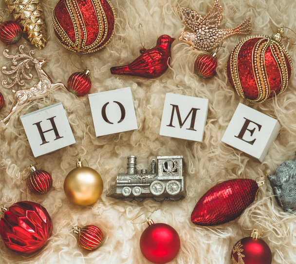 La palabra HOME en el fondo de una piel de oveja cálida natural y un montón de juguetes de Navidad. Año Nuevo 2019 composición. Tiempo de Navidad
 - Foto, Imagen