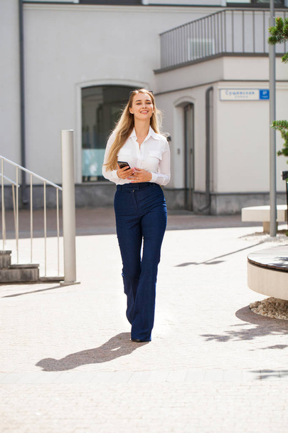 Portrait of a full-length young beautiful business woman in blue jeans and white shirt - 写真・画像
