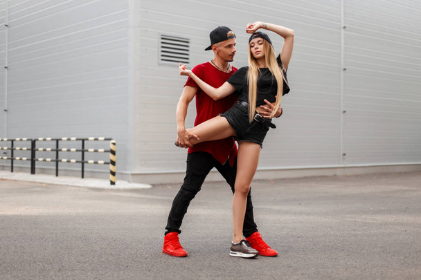 Handsome man with a beautiful young girl dancing breakdance on the street. Street dance - Fotó, kép