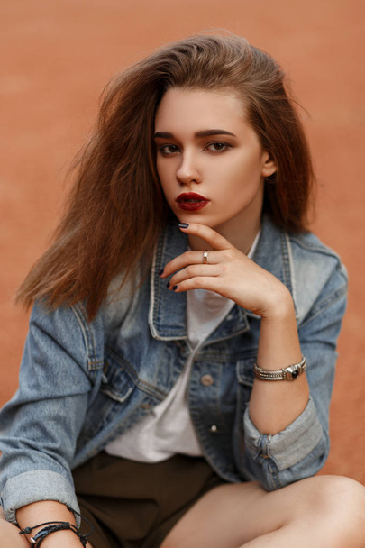 Fashion portrait of a beautiful young female model in a vintage denim jacket outdoors - Photo, Image