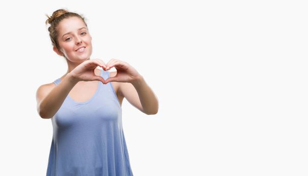 Young blonde woman smiling in love showing heart symbol and shape with hands. Romantic concept. - Фото, зображення