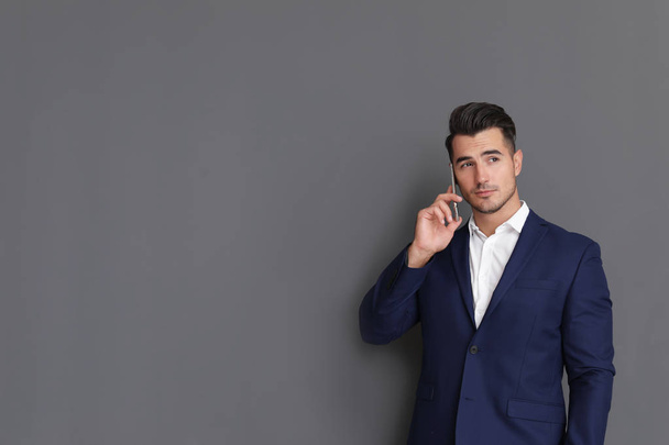 Handsome young man talking on phone against grey background. Space for text - Photo, Image