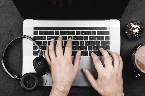 De internetgebruiker handen zoekt een lievelingslied, laptop, koptelefoon, bovenaanzicht - Foto, afbeelding