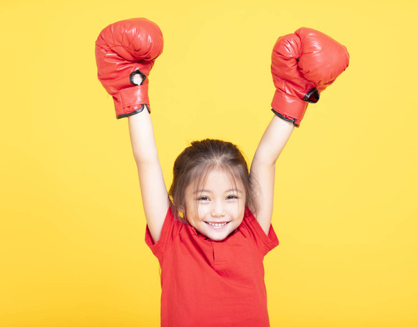 Gelukkig klein meisje met rode bokshandschoenen op gele achtergrond - Foto, afbeelding