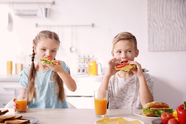 Little children having breakfast with toasts in kitchen - Photo, image