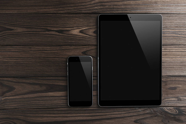 Tablette numérique moderne vierge avec téléphone sur un bureau en bois. Vue de dessus, plan plat. Collage graphique détaillé de haute qualité
 - Photo, image