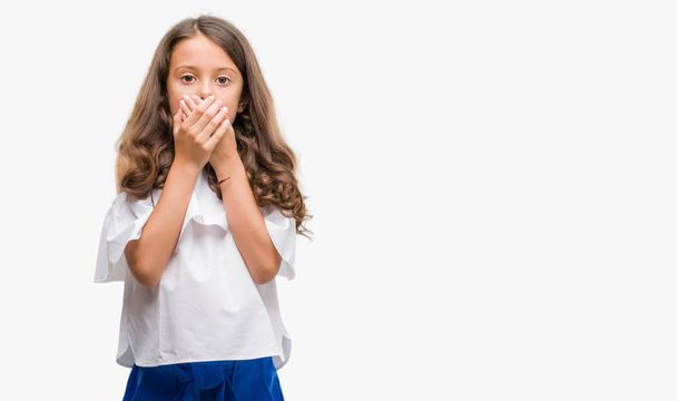 Brünettes hispanisches Mädchen schockiert Mund mit Händen für Fehler bedecken. Geheimes Konzept. - Foto, Bild