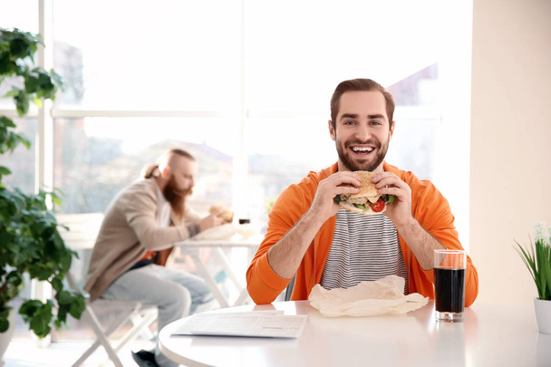 Emotional bearded man with yummy burger against color background - Фото, зображення