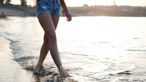 Uitzicht vanaf hieronder van de vrouwelijke benen, een vrouw wandelingen langs de kust, mooie vrouw, wandelen op het strand. De zee spoelt womens voeten. - Video
