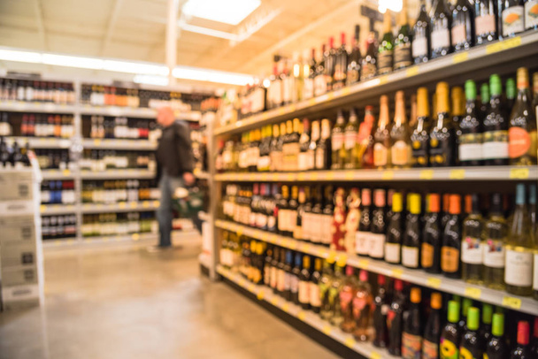 Imagen borrosa de las compras de los clientes en los estantes de vino con etiquetas de precios en la tienda en Houston, Texas, EE.UU.. Filas desenfocadas de botellas de licor en el estante del supermercado. Bebidas alcohólicas antecedentes abstractos
 - Foto, imagen