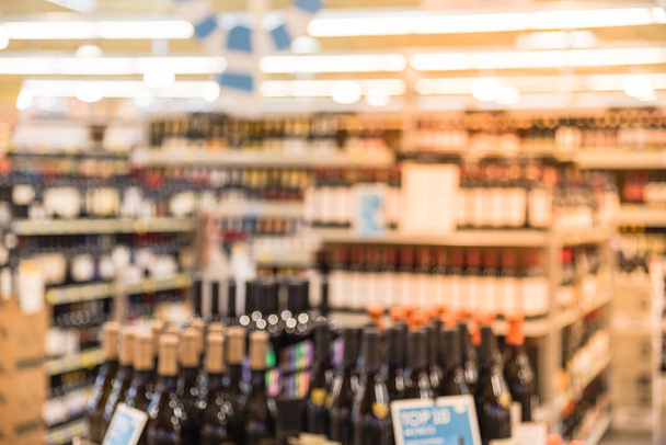 Immagine sfocata degli scaffali dei vini con cartellini dei prezzi esposti nel negozio di Houston, Texas, Stati Uniti. File deconcentrati di bottiglie di vino liquore sullo scaffale del supermercato. Bevanda alcolica sfondo astratto
. - Foto, immagini