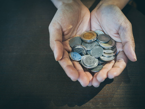 Monedas en manos sobre fondo de mesa de madera. Ahorro de dinero y concepto de donación
. - Foto, imagen
