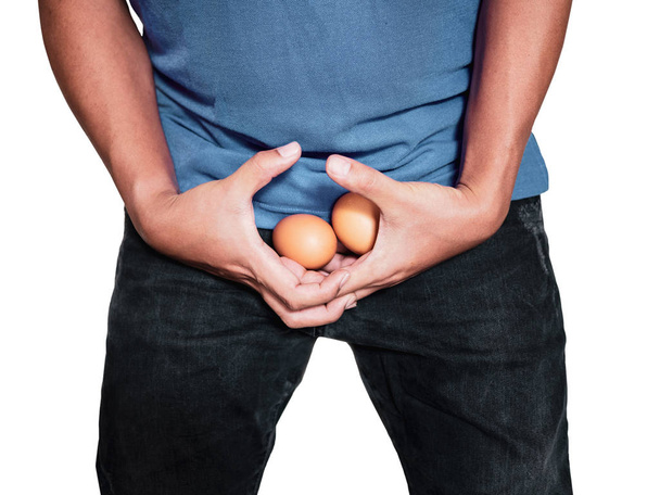 Mężczyzna ręce trzymając jaj na środku krocze spodnie z bólu akcji na białym tle. - Zdjęcie, obraz