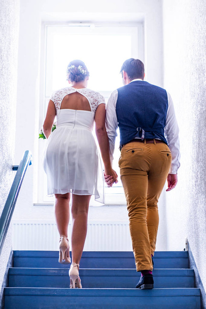 bride and groom in wedding dress holding hand climbing stairs on day of the wedding ceremony the couple together love - Foto, Imagem